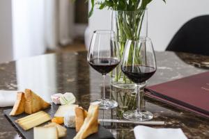 two glasses of red wine and cheese on a table at Hôtel Cardinal Bordeaux Centre in Bordeaux