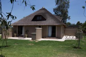 a thatch roofed house with a yard at Inyameko BnB in Centurion