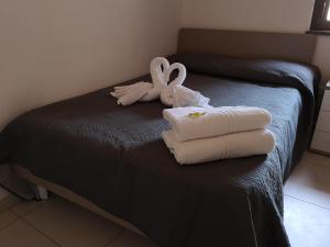 un letto con asciugamani e cigni sopra di mungiBEDdu Apartment a Catania