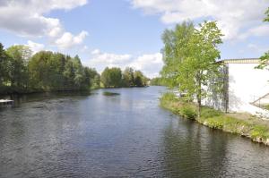 a river with a bridge and trees in the background at Spångholmen B & B in Mjölby