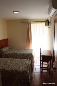 a hotel room with two beds and a desk and a window at Nuevo Hostal Paulino in Trujillo