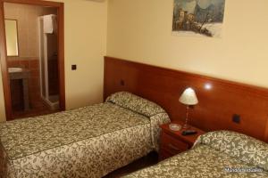 Habitación de hotel con 2 camas y mesa con lámpara en Nuevo Hostal Paulino, en Trujillo