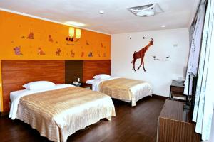 2 Betten in einem Hotelzimmer mit einer Giraffe an der Wand in der Unterkunft Toong Mao Resorts & Hotel in Kenting