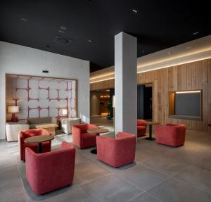 a lobby with red chairs and a flat screen tv at Hotel Ciudad de Logroño in Logroño