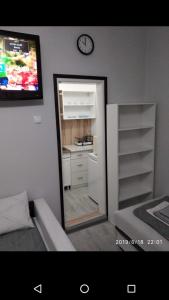 a mirror in a room with a kitchen and a clock at Apartmani Pinokio in Niš