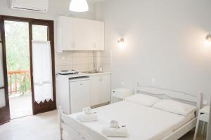 a white bedroom with a bed and a kitchen at Afroditi Pansion in Agios Nikitas
