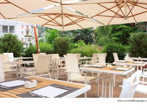 patio z białymi stołami, krzesłami i parasolami w obiekcie Grand Hotel Trento w Trydencie