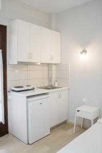 a kitchen with white cabinets and a sink and a stool at Afroditi Pansion in Agios Nikitas