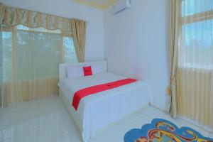 een slaapkamer met een wit bed en een rood kussen bij RedDoorz Syariah near Museum Lambung Mangkurat 2 in Banjarbaru