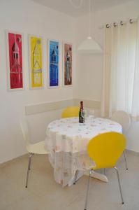 een tafel met twee gele stoelen en een fles wijn bij Villa Matovica in Kampor