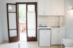 a kitchen with white cabinets and a door to a patio at Afroditi Pansion in Agios Nikitas