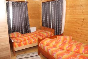 deux lits dans une chambre aux murs en bois dans l'établissement Casa Alex, à Gîrda de Sus