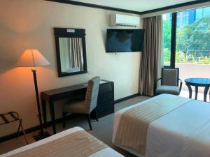 a hotel room with a bedroom with a desk and a bed at Tower Inn Makati Business Hotel in Manila