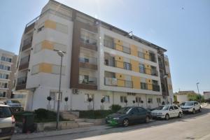 a large white building with cars parked in front of it at Helada Apartments in Tivat