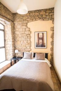 a large bed in a room with a stone wall at Urbi Apartments in Manresa