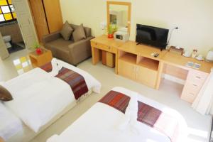 Cette chambre comprend deux lits et une télévision. dans l'établissement ChiangRai Lake Hill, à Chiang Rai