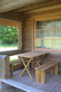 a picnic table on the porch of a log cabin at Purje Holiday Home in Heltermaa