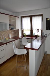 eine Küche mit einer Theke und 2 weißen Stühlen in der Unterkunft Apartmán Karolinka 109 in Karolinka