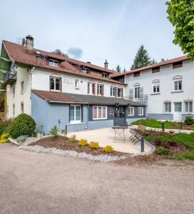 een groot wit huis met een bankje ervoor bij LOGIS Hôtel Restaurant La Vigotte in Girmont-Val-dʼAjol