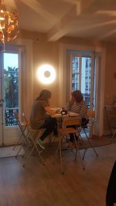 Dos mujeres sentadas en una mesa en una habitación en Hostel Royalty ALBERGUE, en Santander