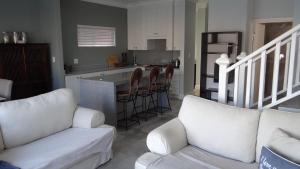 a living room with two white couches and a kitchen at Waterside Living CAN05 in Jeffreys Bay