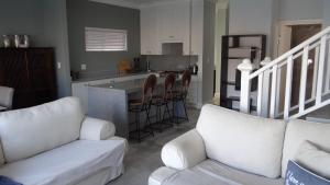 sala de estar con 2 sofás blancos y cocina en Waterside Living CAN05, en Jeffreys Bay
