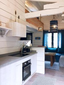 a kitchen with white cabinets and a living room at Les Maisons de pêcheurs in Sète