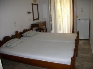 a bedroom with a bed and a table and a refrigerator at Jasmine's Guest House in Karlovasi