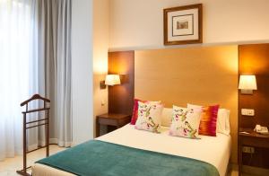 a bedroom with a bed with a wooden headboard and pillows at Suites Barrio de Salamanca in Madrid