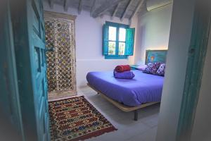 a bedroom with a bed with purple sheets and a window at Riad Puertas del Albaicín in Granada