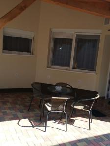 a table and chairs in a room with windows at Gál Apartmanház in Harkány