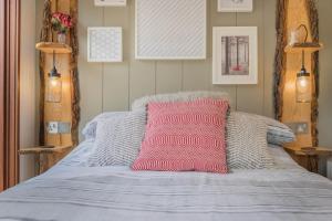 Una cama con una almohada rosa encima. en Dobby Lodge, en Bassenthwaite