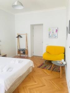 a bedroom with a bed and a yellow chair at Guest House Story in Tbilisi City