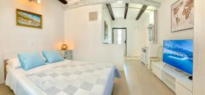 ein weißes Schlafzimmer mit einem Bett und einem TV in der Unterkunft Summer Apartment 2 in Makarska