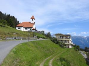 a church on the side of a hill with a house at Apartment Barbara in Mutters