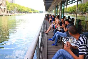 a group of people sitting on a boat on a river at St Christopher's Inn Paris - Canal in Paris