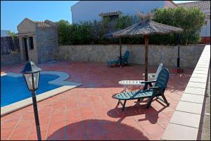patio ze stołem, krzesłami i parasolem w obiekcie Apartamento con piscina comunitaria w mieście Conil de la Frontera