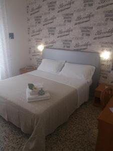 a bedroom with a white bed with a wall with writing at Hotel Barbiani in Riccione
