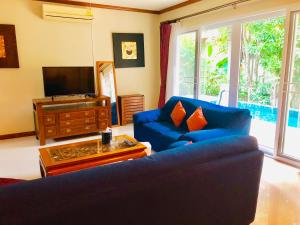 卡隆沙灘的住宿－Karon Pool Villa 卡伦3卧泳池别墅，客厅配有蓝色的沙发和电视