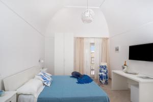 a white bedroom with a blue bed and a desk at Caprita Guest House in Anacapri