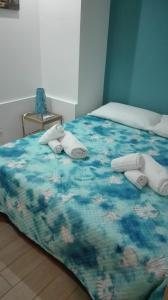 uma cama com um edredão azul com toalhas em Smile's Home em Catânia