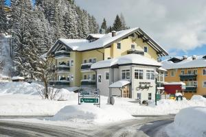 a large yellow building with snow on the ground at Hotel Jagdhof in Filzmoos