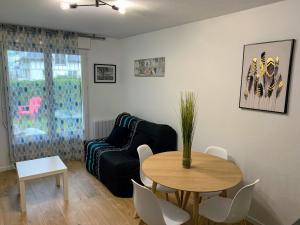 a living room with a table and a couch at FRONT DE MER 11 - JARDIN - THALASSO in Cabourg