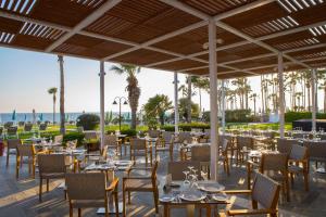 a restaurant with tables and chairs with the ocean in the background at Leonardo Cypria Bay in Paphos