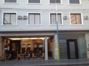 Lorenzo Suites Hotel في سان ميغيل دي توكومان: مبنى يوجد طاولات وكراسي خارجه