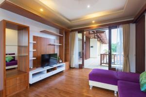 a living room with a purple couch and a tv at Villa Sabasanti Gianyar in Keramas