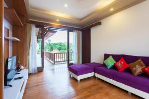 a living room with a purple couch and a tv at Villa Sabasanti Gianyar in Keramas