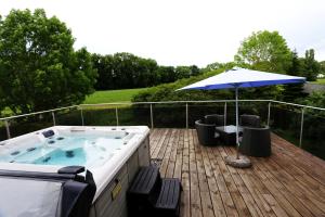 a hot tub on a deck with an umbrella at Villa with Pool - Leon's Holiday Homes in Dottikon