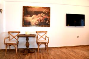 a table and two chairs in a room with a painting at Hotel Messaria in Kithnos