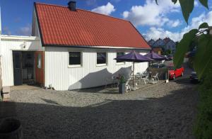 a white building with a red roof and some chairs and umbrellas at Kajsa krabbat Vandrarhem in Kungshamn